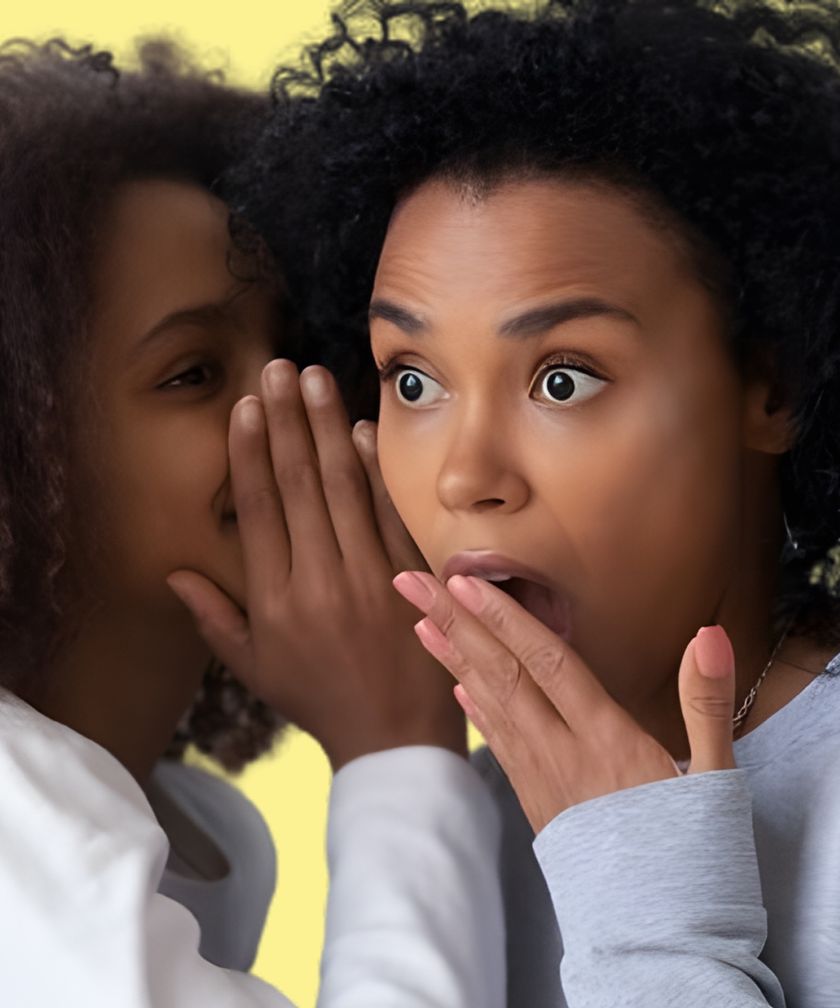 One woman whispers a secret to her friend, who gasps in surprise